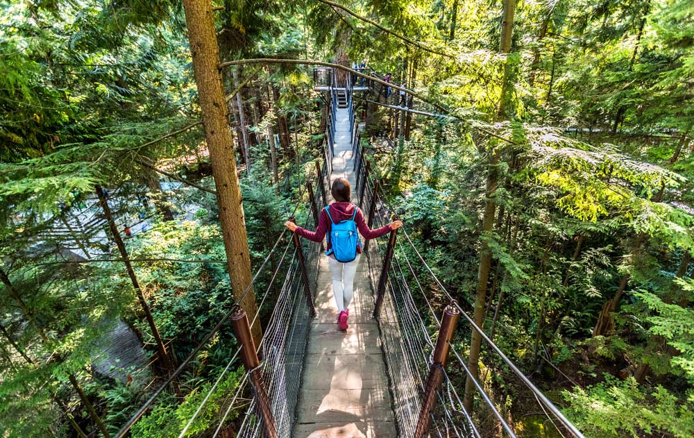 Eine Frau läuft über eine Hängebrücke im Wald